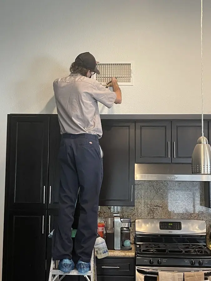 Technician inspecting an air vent during HVAC service in Schroeppel